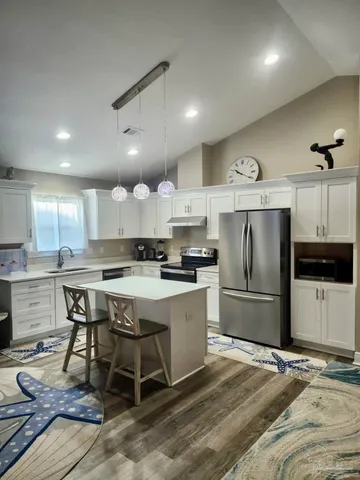 a kitchen with a refrigerator a stove a sink dishwasher with a dining table and chairs