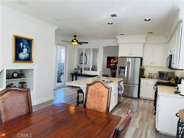 a living room with stainless steel appliances furniture and a wooden floor
