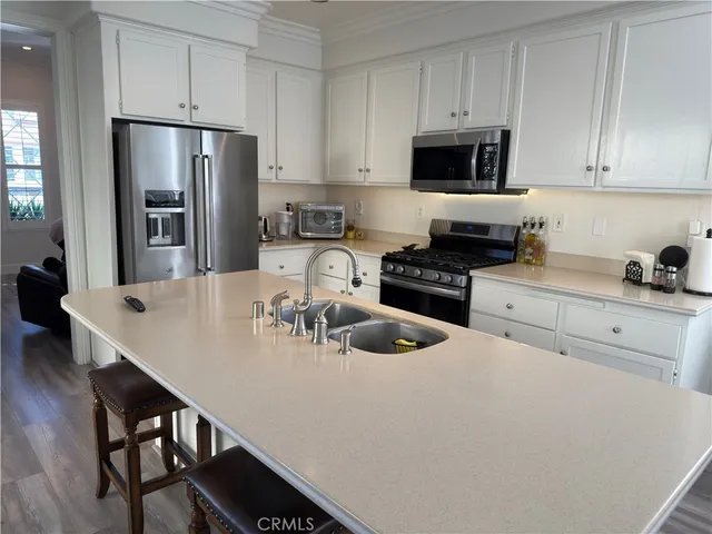 a kitchen with stainless steel appliances a white refrigerator a stove a sink a microwave and dining table