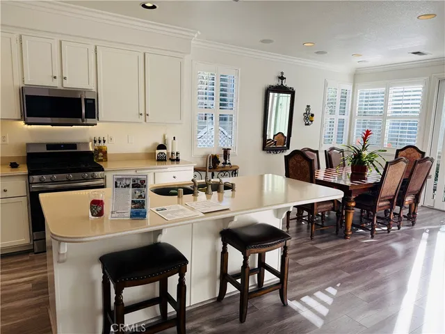 a kitchen with stainless steel appliances a sink dishwasher a refrigerator a stove and white cabinets with wooden floor