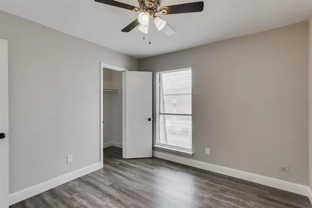 an empty room with wooden floor closet and windows