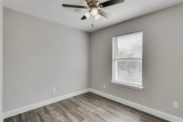an empty room with a window and a fan