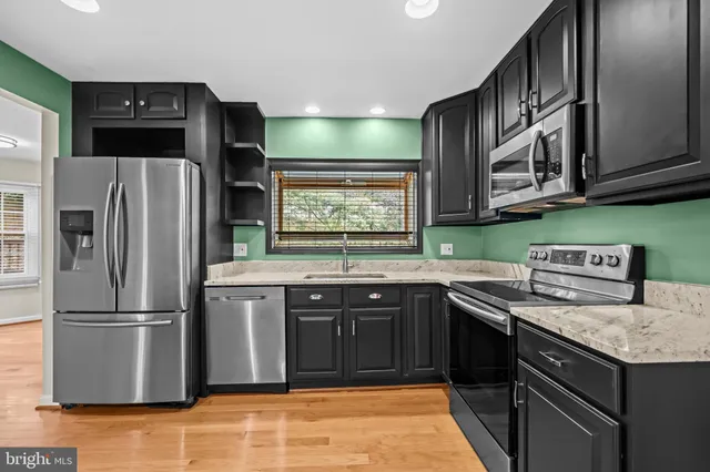 a kitchen with stainless steel appliances granite countertop a stove a refrigerator and a sink