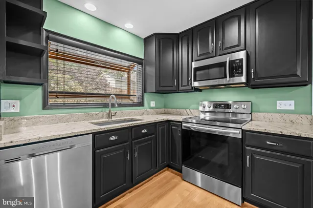 a kitchen with stainless steel appliances granite countertop a sink stove and microwave