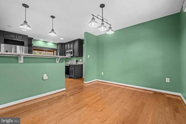 a kitchen with stainless steel appliances granite countertop a refrigerator a stove top oven and a wooden floor