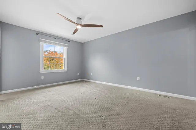 an empty room with windows and ceiling fan