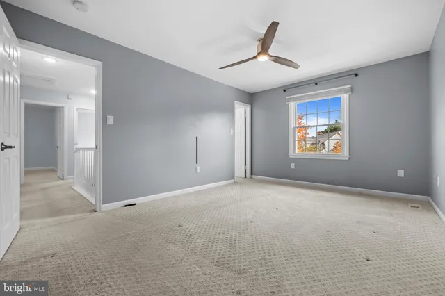 an empty room with windows and ceiling fan