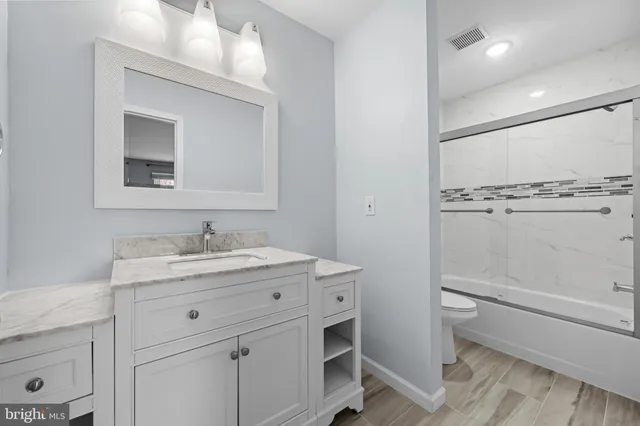 a bathroom with a granite countertop sink toilet a mirror and shower