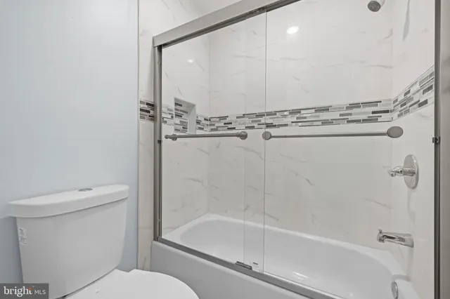 a bathroom with a granite countertop bathtub shower and toilet