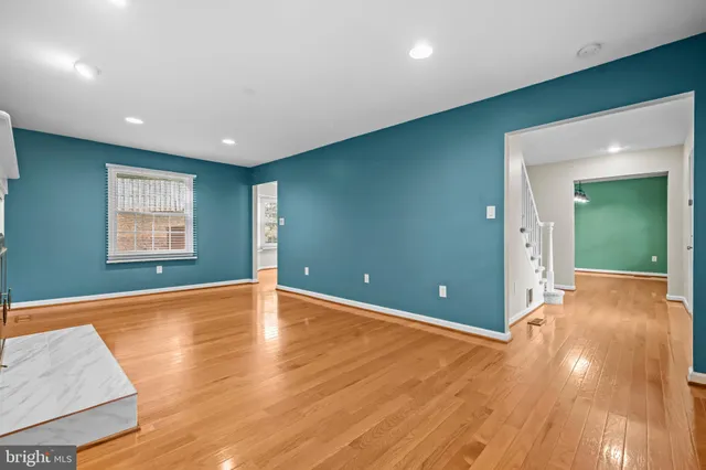 a view of an empty room with wooden floor and windows
