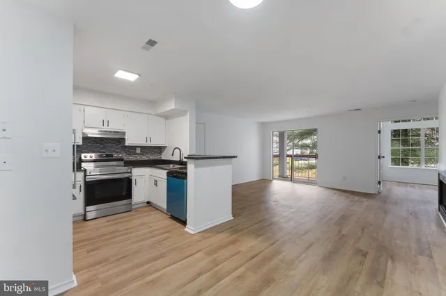 a kitchen with granite countertop a stove top oven a sink dishwasher and a refrigerator with wooden floor