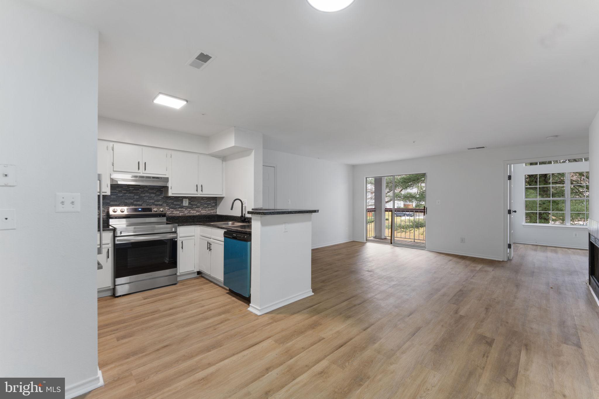 a kitchen with granite countertop a stove top oven a sink dishwasher and a refrigerator with wooden floor