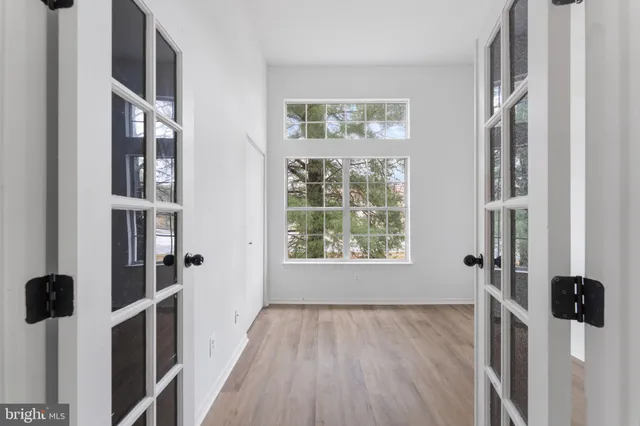an empty room with wooden floor and windows