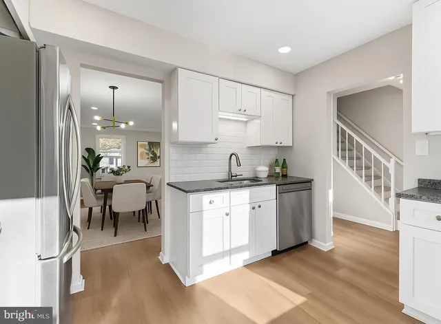 a open kitchen with granite countertop white cabinets and stainless steel appliances