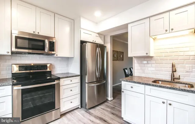 a kitchen with granite countertop a refrigerator stove and microwave