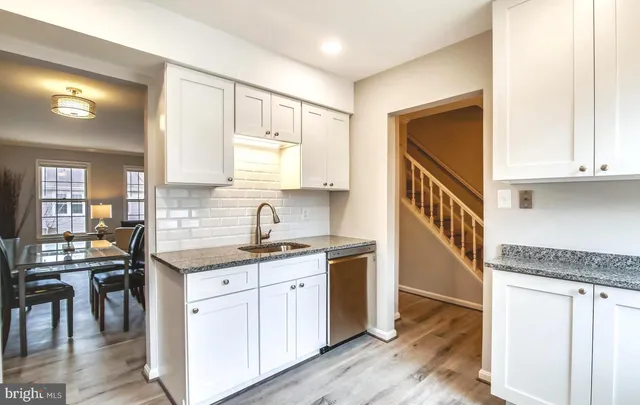 a kitchen with kitchen island granite countertop a sink cabinets and wooden floor