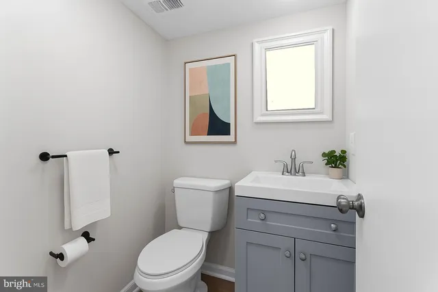 a bathroom with a toilet a sink a mirror and a window