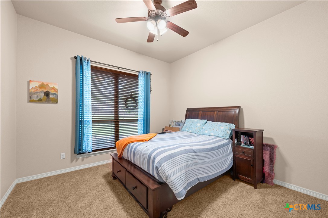 2649 Bowles Ranch Road Belton, TX 76513 - Photo 22 of 36 a bedroom with a bed and a chandelier