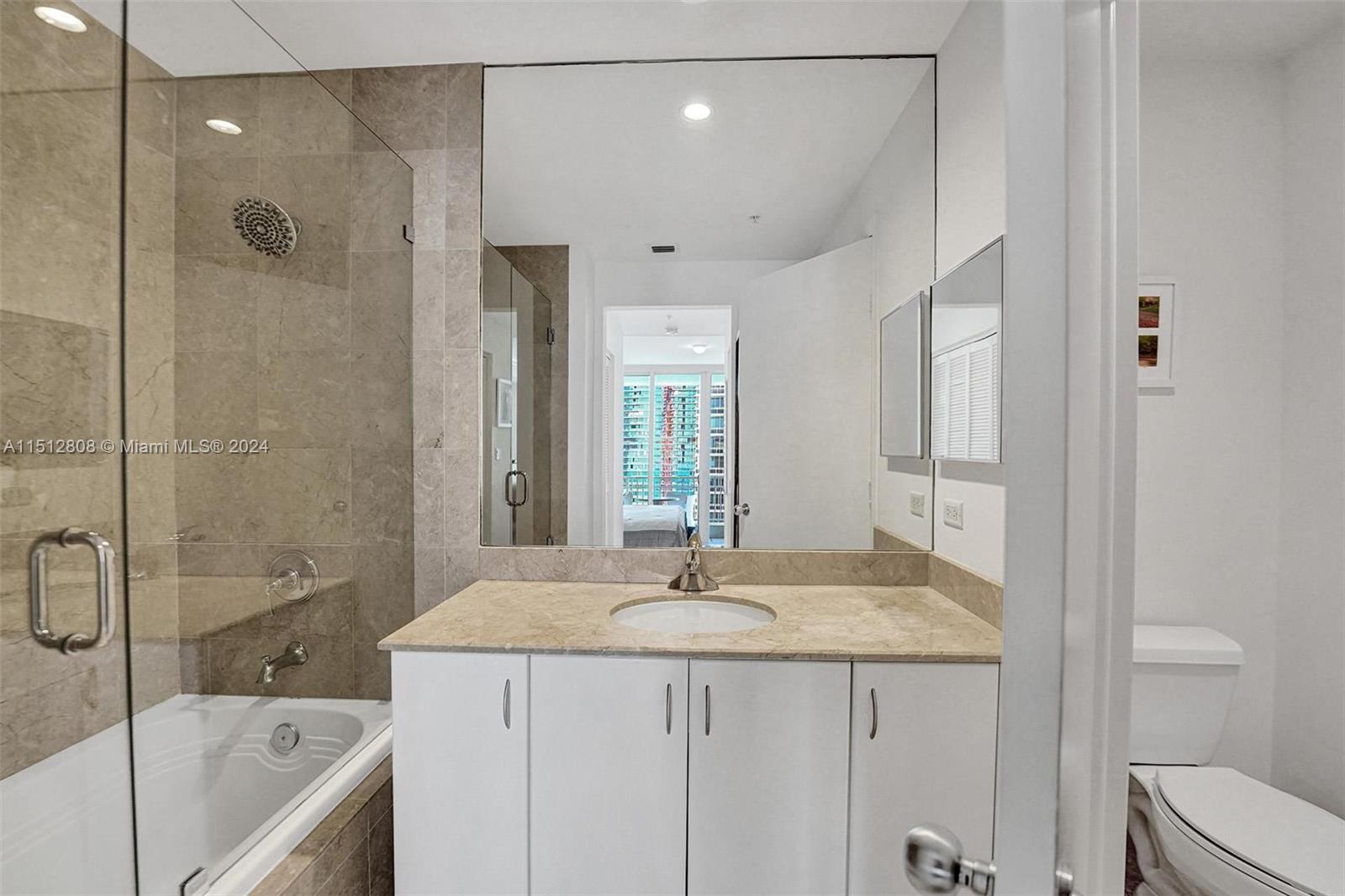 801 Brickell Key Boulevard, Unit 3004 Miami, FL 33131 - Photo 11 of 33 a bathroom with a granite countertop sink a toilet and shower