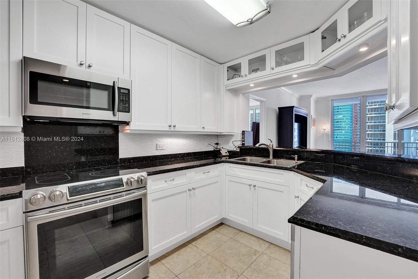 801 Brickell Key Boulevard, Unit 3004 Miami, FL 33131 - Photo 4 of 33 a kitchen with granite countertop a stove sink and microwave