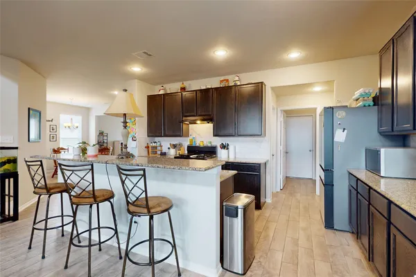 a kitchen with stainless steel appliances a dining table chairs refrigerator and microwave