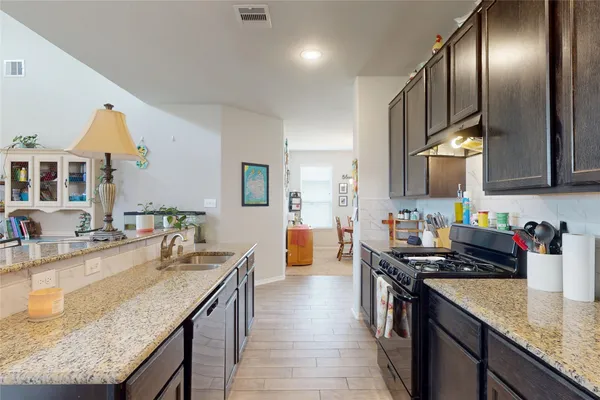a kitchen with stainless steel appliances granite countertop a sink a stove and a wooden floors