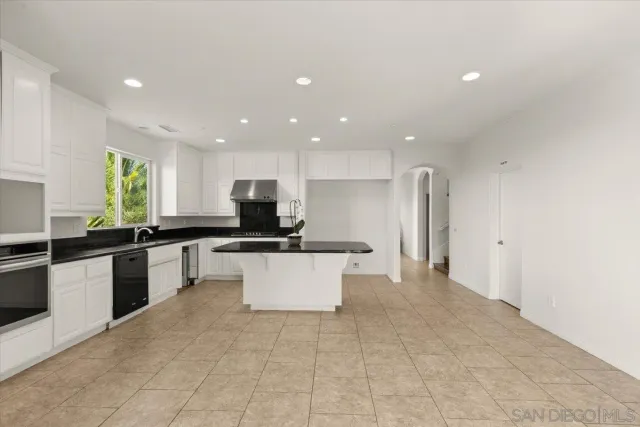 a large kitchen with stainless steel appliances a large counter top and a stove top oven