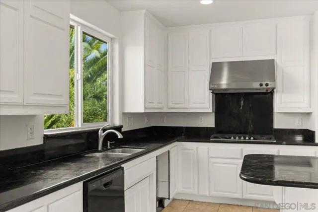 a kitchen with granite countertop a sink a stove and cabinets