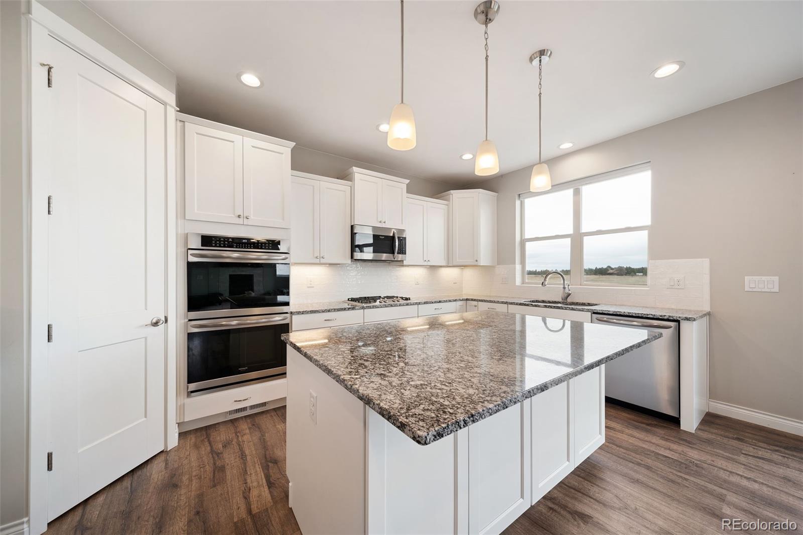 240 High Meadows Loop Elizabeth, CO 80107 - Photo 21 of 50 a kitchen with stainless steel appliances granite countertop a sink a stove a refrigerator and island with wooden floor