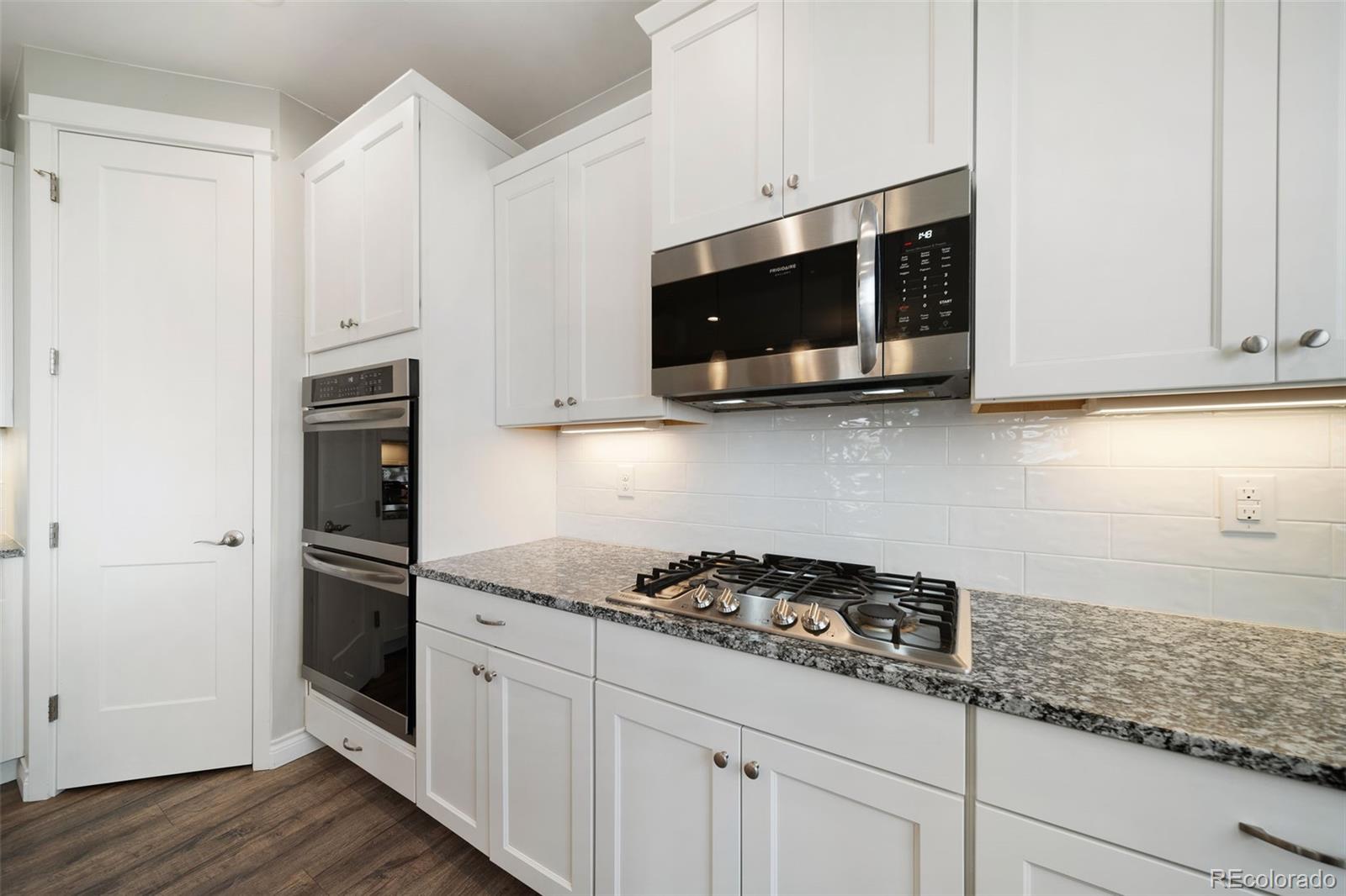 240 High Meadows Loop Elizabeth, CO 80107 - Photo 24 of 50 a kitchen with stainless steel appliances granite countertop white cabinets and a stove a oven with wooden floor