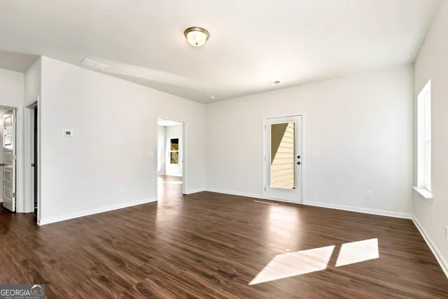 a view of an empty room with wooden floor and a window