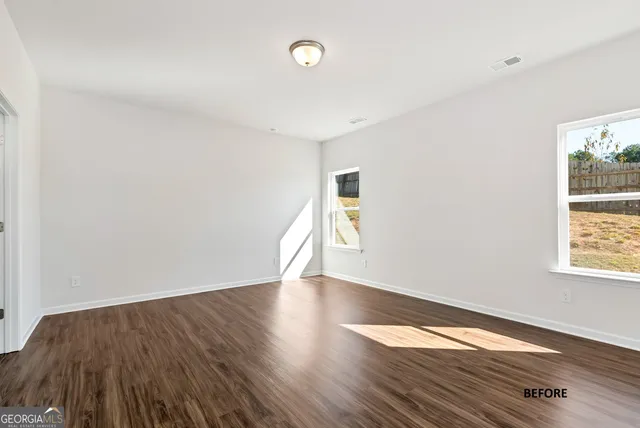 an empty room with wooden floor and windows