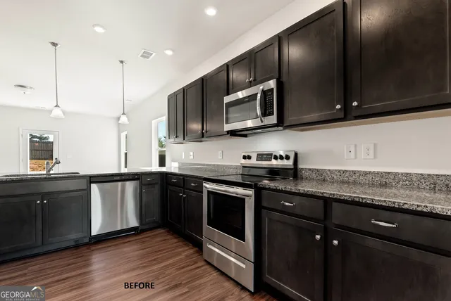a kitchen with stainless steel appliances granite countertop a sink a stove top oven and wooden cabinets