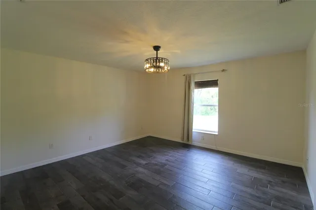 an empty room with wooden floor and chandelier fan