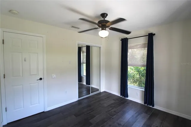 a view of a hallway with wooden floor and a ceiling fan