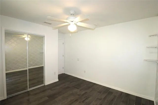 an empty room with wooden floor fan and window