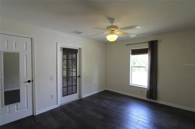 an empty room with wooden floor closet and windows
