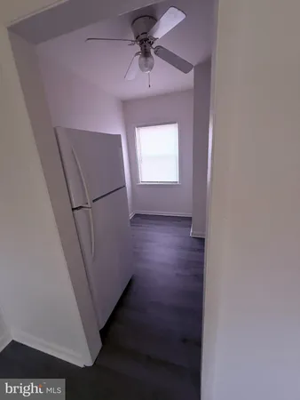 a view of a hallway to a bedroom with wooden floor and a ceiling fan