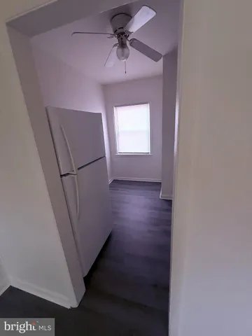 a view of a hallway to a bedroom with wooden floor and a ceiling fan