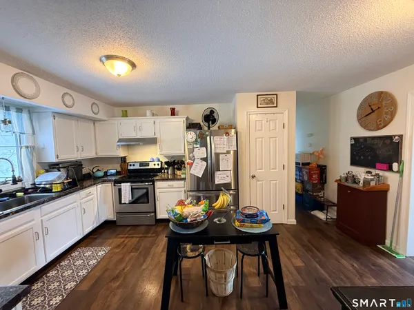 a kitchen with stainless steel appliances kitchen island granite countertop a table chairs stove and cabinets