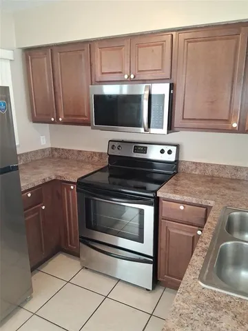 a kitchen with granite countertop a stove top oven microwave and cabinets