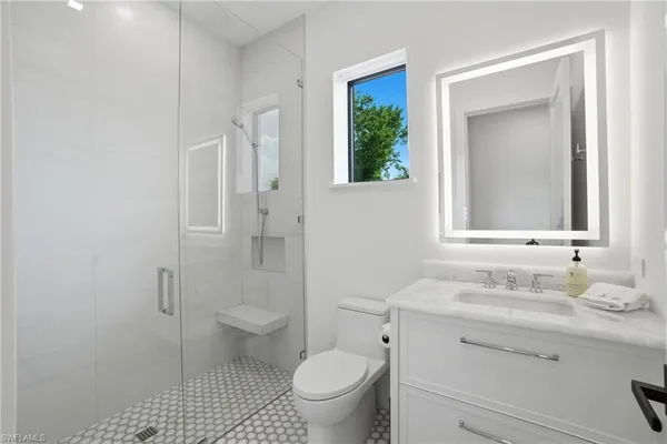 a bathroom with a granite countertop toilet a sink and a mirror
