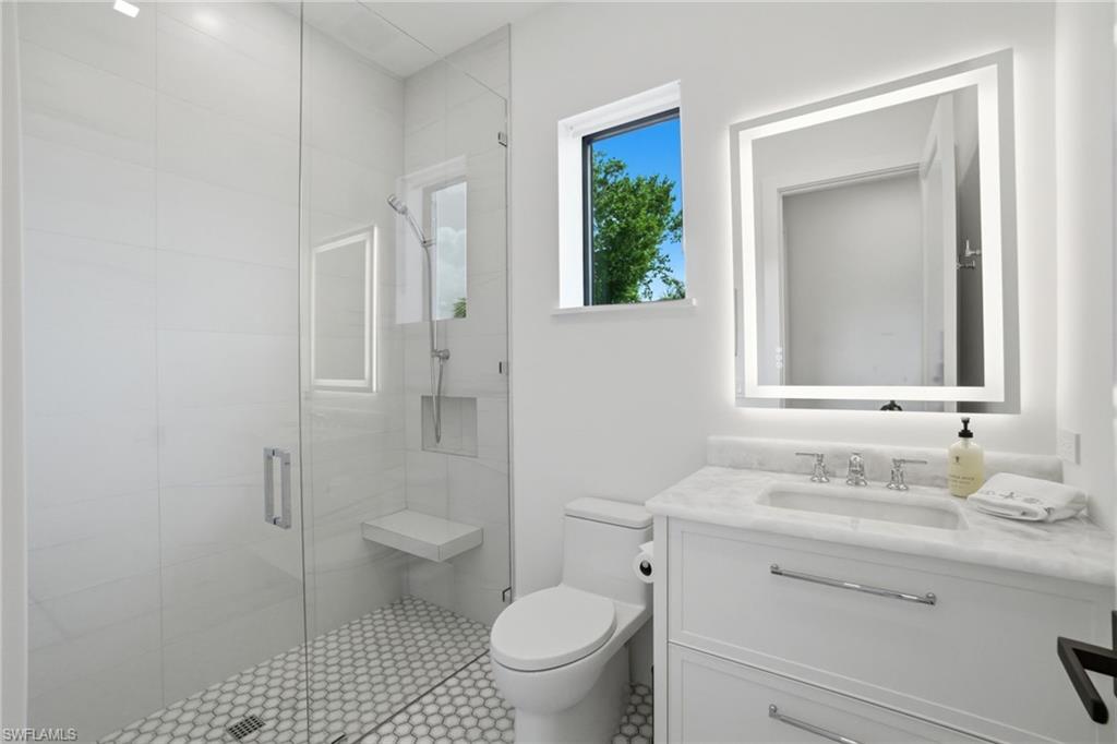 264 8th Avenue South Naples, FL 34102 - Photo 21 of 40 a bathroom with a granite countertop toilet a sink and a mirror