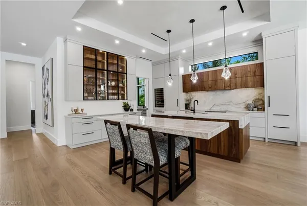 a kitchen with stainless steel appliances granite countertop a sink a stove a refrigerator and island with wooden floor