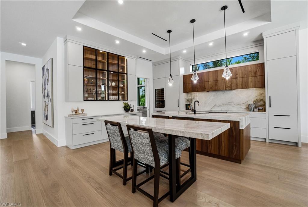 264 8th Avenue South Naples, FL 34102 - Photo 5 of 40 a kitchen with stainless steel appliances granite countertop a sink a stove a refrigerator and island with wooden floor