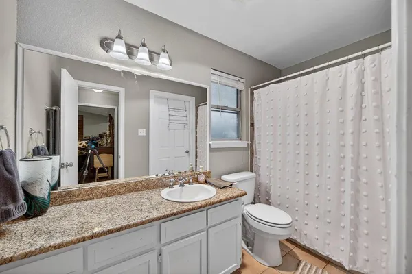 a bathroom with a granite countertop sink a toilet and a mirror