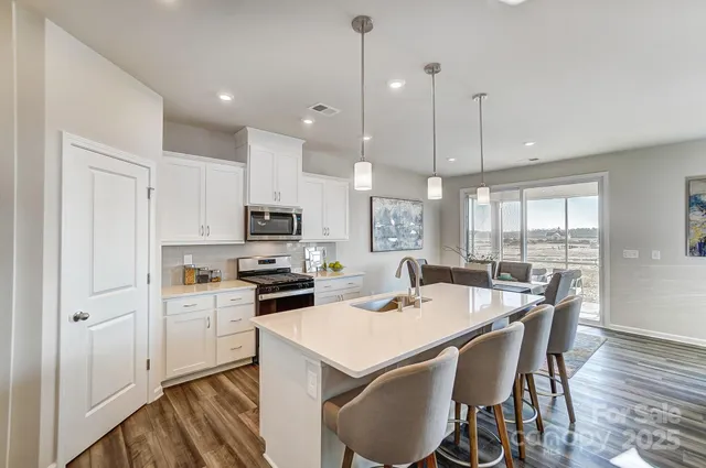 a kitchen with a stove a refrigerator and a dining table with wooden floor