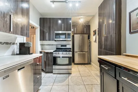 a kitchen with stainless steel appliances granite countertop a refrigerator a stove and a sink