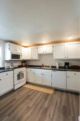 a large white kitchen with stainless steel appliances granite countertop a stove a sink and white cabinets