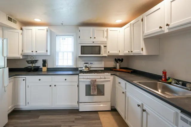 a kitchen with granite countertop white cabinets white stainless steel appliances and sink
